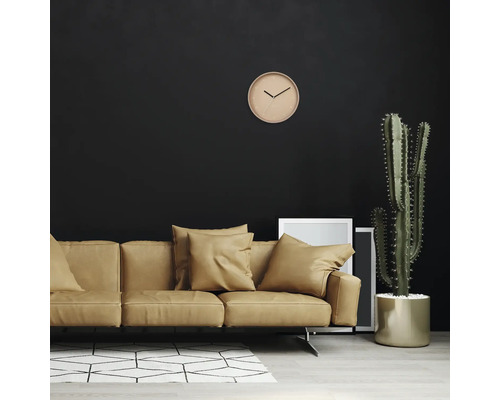 Vardagsrum med soffa, kaktus, klocka och fotoramar mot en mörk vägg