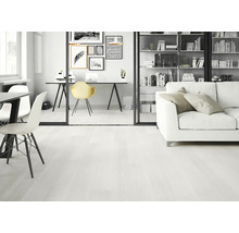 Ljust vardagsrum med skrivbord, hyllor och soffa på trägolv