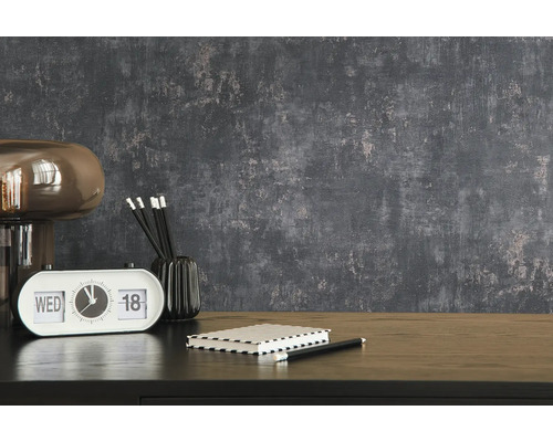 Dekorativ interiör med lampa, bordsklocka, anteckningsblock och pennor på ett bord framför en strukturerad vägg