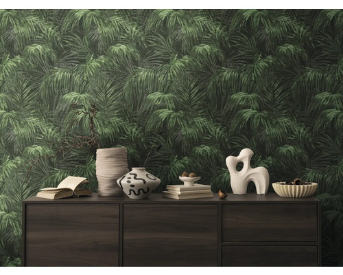 Närbild av en vägg med en tapet med bladmotiv som skapar en tropisk atmosfär