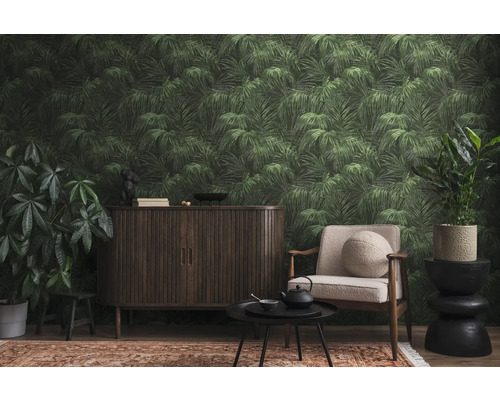 Vardagsrum med mörka möbler, fåtölj, krukväxter och tapet med palmblad