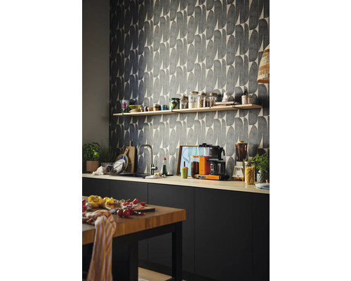 Köksscen med grafisk tapet, bänkskiva, hyllor och köksredskap.