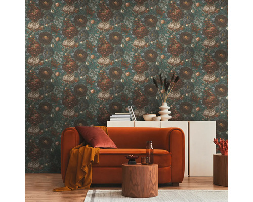 Ett vardagsrum med en blommig tapet, en soffa, ett sidobord och en byrå.