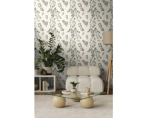 Vardagsrum med blommig tapet, fåtölj, bord och krukväxter.