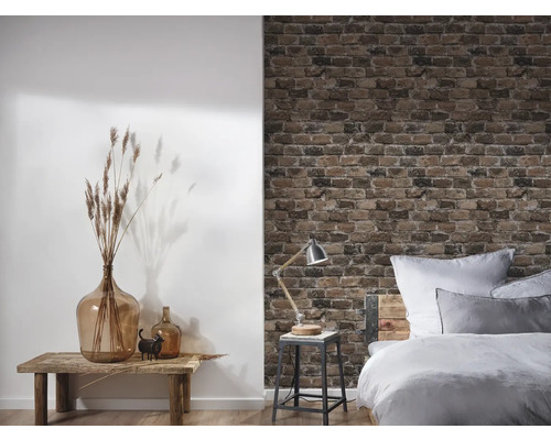 Dekorativt rum med säng, bord, lampa, vas och tapet med tegelstensmönster