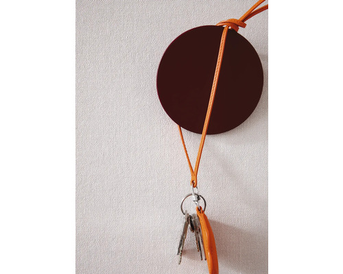 Rund nyckelhållare med läderband på en vägg med nycklar