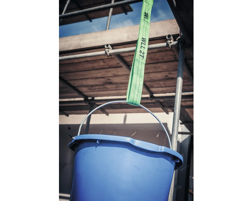 Blå hink hänger i en grön lyftrem framför en byggnadsställning.