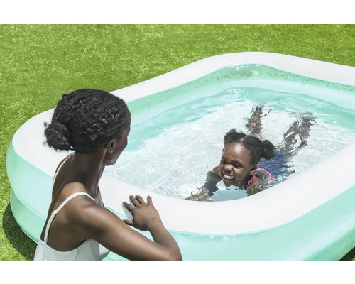 Mamma och barn i uppblåsbar pool i trädgården