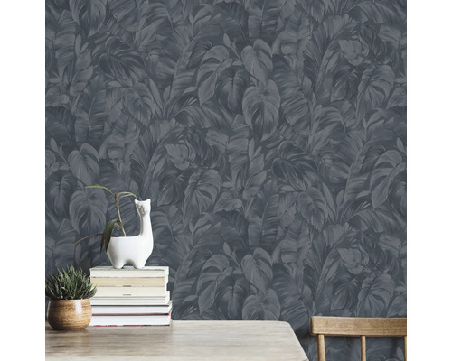 Vägg med mörk bladformad tapet, dekorerad med växter och böcker.