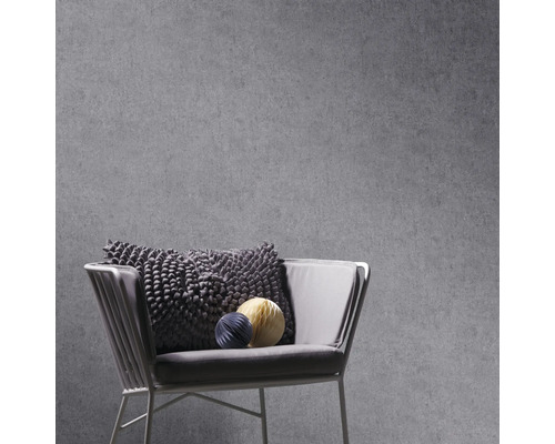 Grå betongtapet med fåtölj och dekorativa kuddar