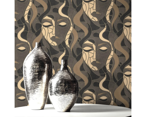 Två silverfärgade vaser på ett bord framför en mönstrad tapet med ansikten.