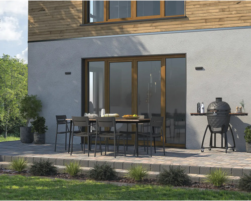 Uteplats med trädgårdsbord, stolar och keramisk grill vid bostadshuset