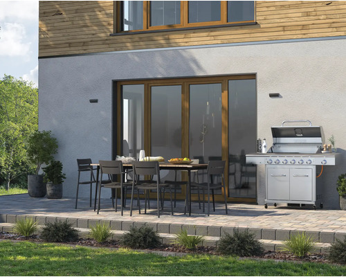 Terrass med grill, trädgårdsbord och stolar framför husfasad