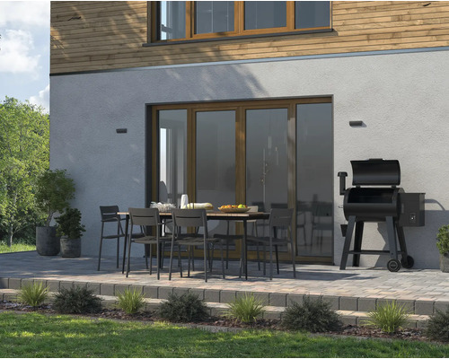 Uteplats med matbord, stolar och grill bredvid huset