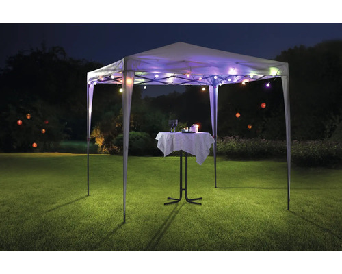 Paviljong med ljusslinga och bistrobord på en gräsmatta