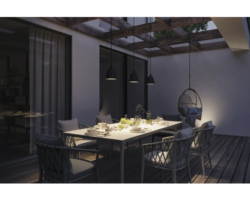 Terrass med matbord, stolar och hänglampor under en pergola