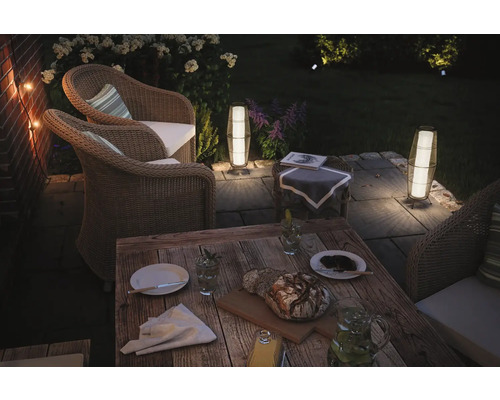 Terrass med rottingmöbler, träbord och dekorativ utomhusbelysning