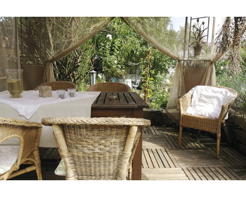 Dekorerat trädgårdsbord med rottingstolar i en ljus och vänlig atmosfär.