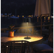 Utomhusbild av en bordslampa på ett träbord utomhus på natten.