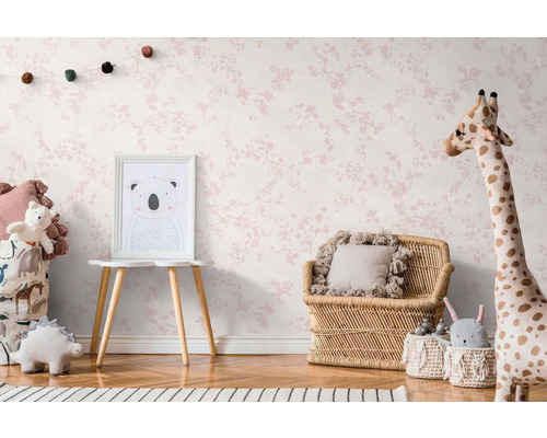 Barnrum med blommönstrad tapet, rottingmöbler och gosedjur.