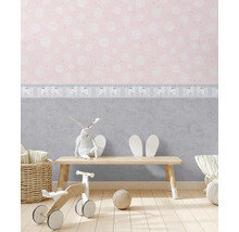 Barnrum med mönstrad tapet, leksaker och trämöbler för en ljus och vänlig atmosfär.