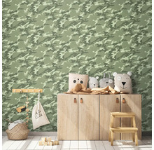 Dekorerat barnrum med väggtapet med kamouflagemönster, träskåp, prydnadskuddar, förvaringskorg och leksaker