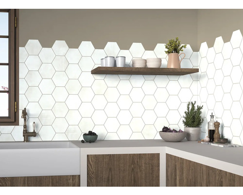 Köksscen med vita, hexagonala plattor på väggen, kompletterat med en trähylla och en arbetsbänk