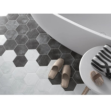 Badrum med sexkantiga golvplattor, badkar, handduk och tofflor