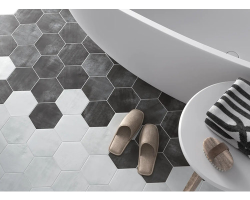 Badrum med sexkantiga golvplattor, badkar, handduk och tofflor