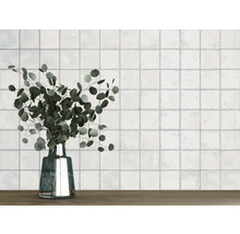 Vägg med kvadratiska plattor och en vas med eukalyptus på ett träbord