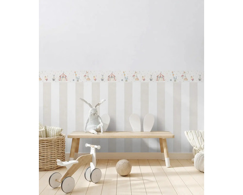 Barnrum med randig tapet, cirkusfris, leksaker och träbänk.