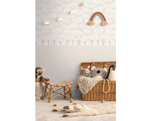 Dekorerat barnrum med molntapet, regnbågs väggdekoration, rottingpall och leksaker i en korg.