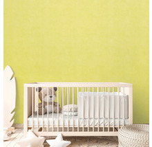 Babyrum med spjälsäng, teddybjörn och dekorativa element framför en ljusgul vägg