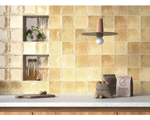 Köksvägg kaklad med fyrkantiga plattor, hyllor, dekorationer och matvaror