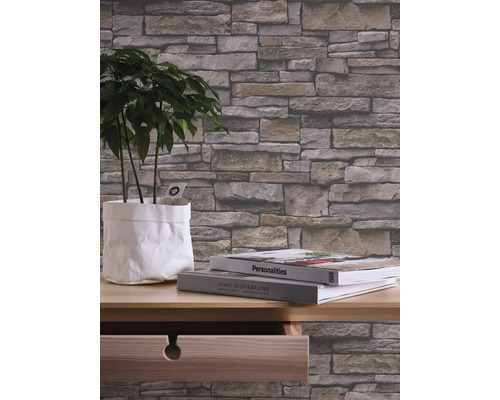 Närbild av en tapet med stenmotiv i ett rum med en växt och böcker på ett bord.