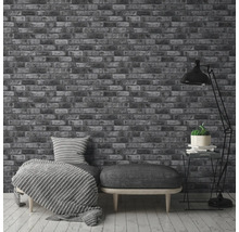 Interiör med en tapet med tegelmotiv, en soffa med kuddar och en golvlampa