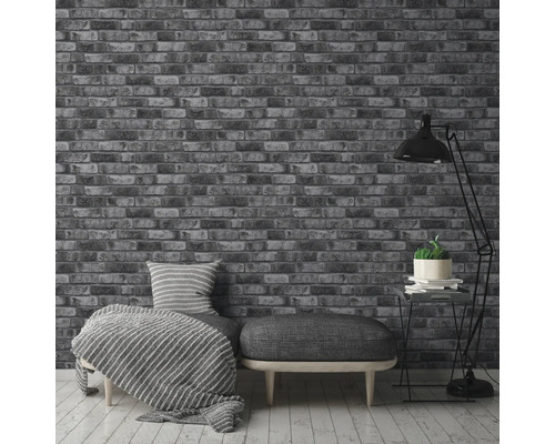 Interiör med en tapet med tegelmotiv, en soffa med kuddar och en golvlampa