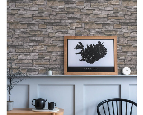 Vardagsrum med en vägg med tapet i stenlook och en inramad Island-affisch