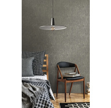 Miljöbild med säng, stol, lampa och en strukturerad tapet