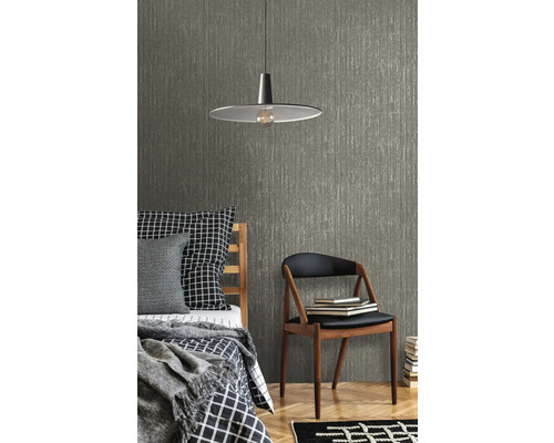 Miljöbild med säng, stol, lampa och en strukturerad tapet
