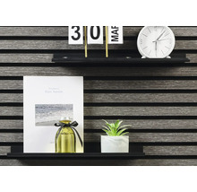 Dekorativa föremål på en hylla: kalender, klocka, anteckningsbok, doftflaska och krukväxt.