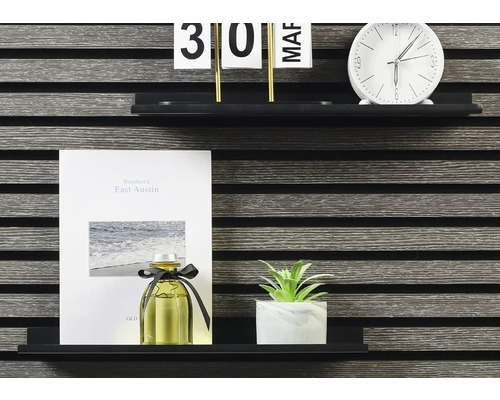 Dekorativa föremål på en hylla: kalender, klocka, anteckningsbok, doftflaska och krukväxt.