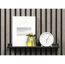 Dekorativ scen med anteckningsbok, doftflaska och klocka på en hylla