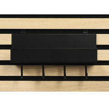 Svart hylla med krokar på en träpanelvägg