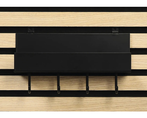 Svart hylla med krokar på en träpanelvägg