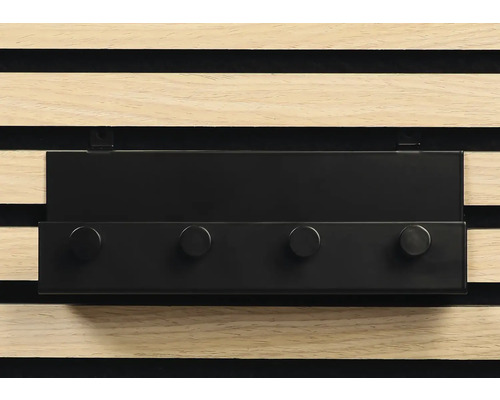 Svart kroklist med fyra krokar framför en träpanelvägg