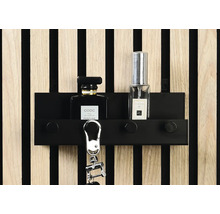 Nyckelskåp med nyckelring och parfymflaskor framför en vägg med träpanel