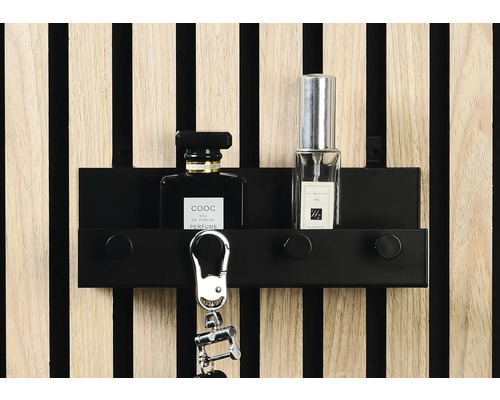 Nyckelskåp med nyckelring och parfymflaskor framför en vägg med träpanel