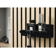 Svart nyckelhållare med krokar och två parfymflaskor på en vägg med träpanel