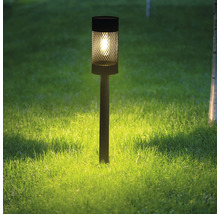 Dekorativ trädgårdslampa av metall på en gräsmatta.